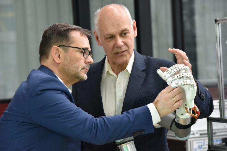 Prof. Stefan Seelecke erklärt an der Roboterhand die Funktion von Muskeln aus Formgedächtnislegierung (SMA)